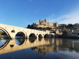 a bridge over a river with a castle in the background at Situation parfaite, calme et spacieux, Wifi fibre, Netflix & Prime in Béziers