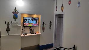 Cette chambre est dotée d'une télévision murale avec quelques décorations. dans l'établissement ADH Amilia Gardens, à Mysore