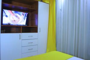 a bedroom with a tv and a bed with a yellow curtain at Madinty Stay in Madinaty