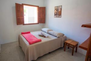 a bedroom with a bed with two pillows and a window at Pousada Recanto do Rio, Jambreiro, Caraiva in Porto Seguro