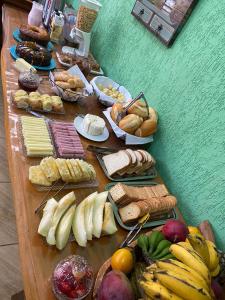una mesa llena de diferentes tipos de pan y fruta en Chalés Sapucaí Pousada, en São Bento do Sapucaí