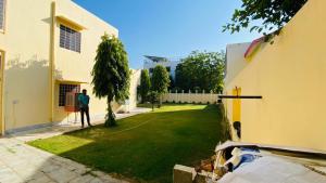 斋浦尔Saket Guest House Jaipur的站在建筑物旁的院子中的男人