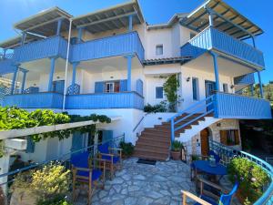 una casa con balcones azules, mesas y sillas en Pantazis Studios in Agios Nikitas en Áyios Nikítas