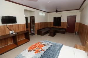 a bedroom with a bed and a flat screen tv at Jain Residency in Pachmarhī