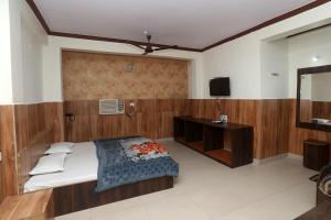 1 dormitorio con 1 cama y TV en Jain Residency en Pachmarhī