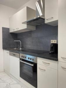 a kitchen with white cabinets and a stove top oven at Apartment Rot-Kreuz in Bad Säckingen