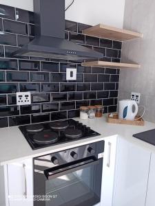 una cocina con fogones y una pared de azulejos negros en Palm Tree en Ciudad del Cabo