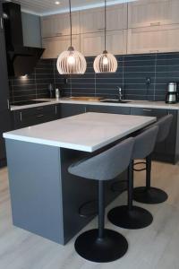 a kitchen with a white counter and two bar stools at Moderne panoramaleilighet 3-roms i Olden in Olden