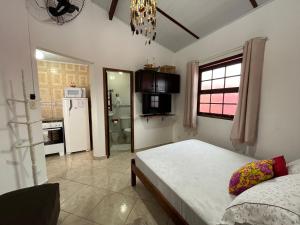 a bedroom with a bed and a kitchen with a refrigerator at Hospedagem Villa Caiçara in Paraty