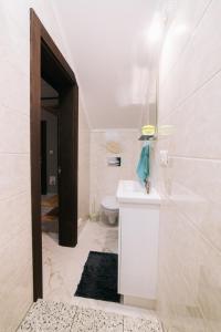 La salle de bains est pourvue d'un lavabo blanc et de toilettes. dans l'établissement Котедж "Під Горбком", à Korchin