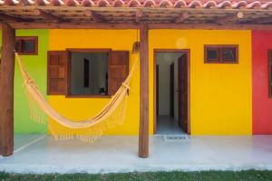 a colorful house with a hammock in front of it at Pousada Recanto do Rio, Jambreiro, Caraiva in Porto Seguro