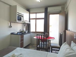 Habitación con cocina y mesa pequeña con sillas. en Flat Sol, en Balneário Camboriú