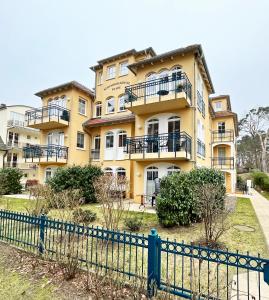 a yellow building with a fence in front of it at Ferienwohnung Strandflair in Baabe