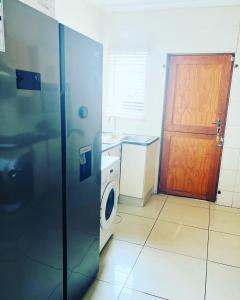 uma cozinha com uma porta e uma máquina de lavar roupa em Cozy Corner Guesthouse em Richards Bay
