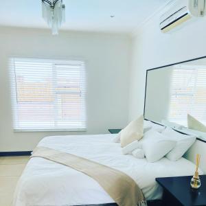 ein weißes Schlafzimmer mit einem großen Bett mit weißen Kissen in der Unterkunft Cozy Corner Guesthouse in Richards Bay