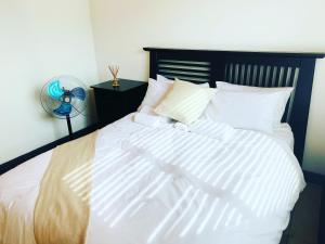 Schlafzimmer mit einem Bett mit weißer Bettwäsche und einem Ventilator in der Unterkunft Cozy Corner Guesthouse in Richards Bay