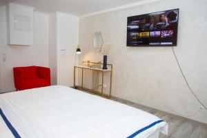 a bedroom with a white bed and a red chair at Ferienhaus Kaimt Zell in Zell an der Mosel