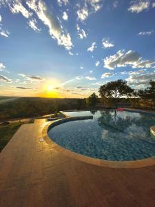 a large swimming pool with a sunset in the background at Pousada Cristal Dourado in Mateiros