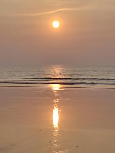 a sunset on the beach with the sun reflecting in the water at Mauli Cottage in Kashid