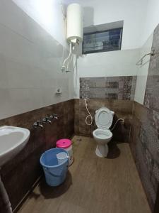 a bathroom with a toilet and a sink and a bucket at M Cube Service Apartments in Sakleshpur