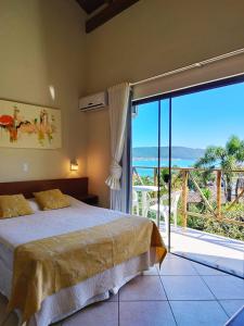 1 dormitorio con cama y vistas al océano en Pousada Aquarela de Bombinhas, en Bombinhas