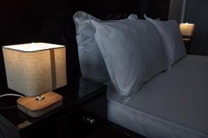 a bed with a white pillow and a lamp on a night stand at Sublime appartement à Cocody Riviera Bonoumin . in Abidjan