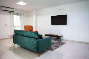 uma sala de estar com um sofá verde e uma televisão em Sublime appartement à Cocody Riviera Bonoumin . em Abidjan