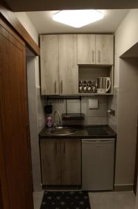 una pequeña cocina con armarios de madera y fregadero en Kovács apartman Harkány en Harkány