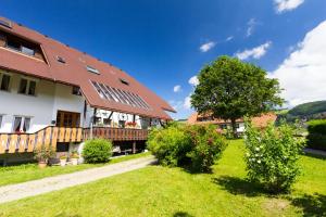 uma casa com um telhado vermelho e um jardim verde em Ferienwohnung Jasmin em Wieden