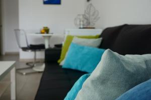 un divano nero con cuscini colorati in soggiorno di Blue Ocean Corralejo: Sunny terrace, pool, wifi a Corralejo