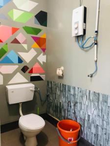 ein Bad mit einem WC und einer farbenfrohen Wand in der Unterkunft WAN'S ROOMSTAY LANGKAWI in Pantai Cenang