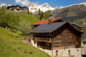 a wooden house on a hill with mountains in the background at Alpenlodge Tgèsa Surrein Giassa10 in Sedrun