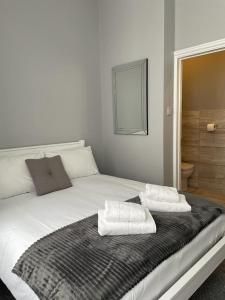 Una cama blanca con dos toallas encima. en Ravna Gora en Londres