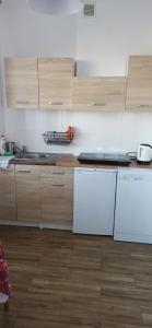 a kitchen with white appliances and wooden cabinets at Apartamenty pod zaglami Teresa Strzemkowska in Białogóra