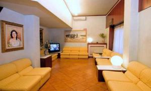 a living room with yellow couches and a television at Piccolo Hotel in Milan