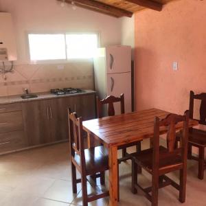 cocina con mesa de madera, sillas y nevera en El Jacaranda 2 - Complejo en Agua de Oro