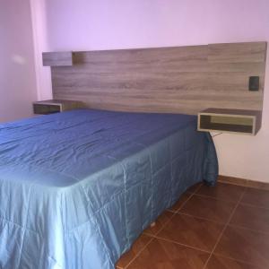 um quarto com uma cama e uma cabeceira em madeira em El Jacaranda 2 - Complejo em Agua de Oro