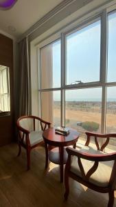 a living room with a table and chairs and a large window at Fakher Yanbu 3 Furnished Units in Yanbu