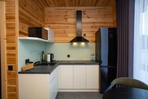 a kitchen with white cabinets and a black refrigerator at Perlyna Resort in Cherkasy