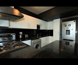a kitchen with white cabinets and a stove top oven at Fountain Suites Aparthotel - PRIVATE in Cape Town