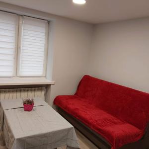 uma sala de estar com um sofá vermelho e uma mesa em Apartament przy kładce em Przemyśl