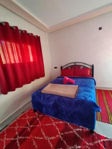 1 dormitorio con cama azul y cortinas rojas en auberge restaurant tizgui, en Tinerhir