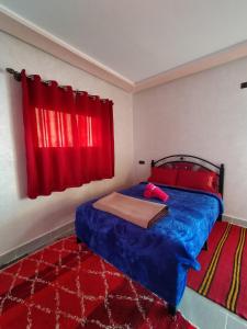 1 dormitorio con cama azul y cortina roja en auberge restaurant tizgui, en Tinerhir