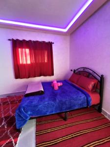 um quarto com uma cama azul com um brinquedo cor-de-rosa em auberge restaurant tizgui em Tinghir