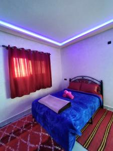 um quarto com uma cama azul com um bicho de peluche cor-de-rosa em auberge restaurant tizgui em Tinghir