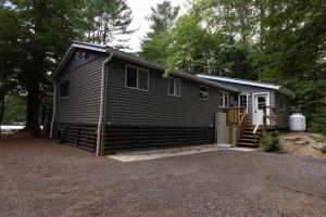 a small black house with a porch and a garage at Cozy Accessible Waterfront Cottage on Healey Lake in Bracebridge