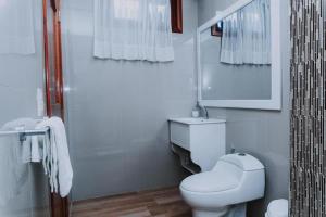 La salle de bains blanche est pourvue de toilettes et d'un lavabo. dans l'établissement Galápagos Isabela Hotel Loja, à Puerto Villamil