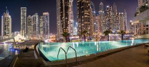 a large swimming pool in a city at night at Dulive in Dubai