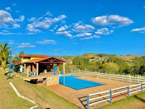 a villa with a swimming pool and a house at Chácara com 4 Chalés, grande piscina e muito verde in Atibaia
