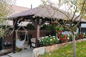 a wooden gazebo with a swing and flowers at Ande House in Orşova